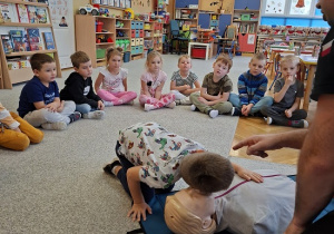 Pan strażak objaśnia dzieciom udzielanie pierwszej pomocy na fantomie