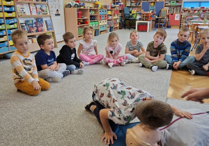 Pan strażak objaśnia dzieciom udzielanie pierwszej pomocy na fantomie