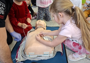 Pan strażak objaśnia dzieciom udzielanie pierwszej pomocy na fantomie