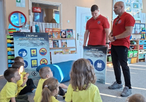 dzieci siedzą i słuchają w żółtych koszulkach