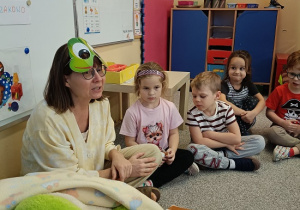 Pani Beatka w masce żabki opowiada dzieciom bajkę