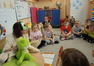 Pani Beatka w masce żabki opowiada dzieciom bajkę