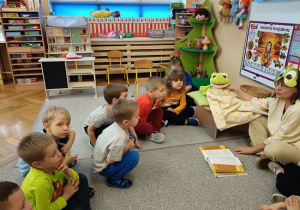 dzieci słuchają bajki siedząc na wykładzinie