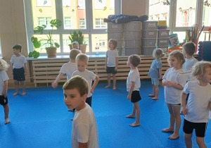 dzieci w strojach gimnastycznych ćwiczą na materacach