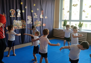 dzieci w strojach gimnastycznych ćwiczą na materacach