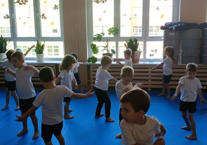 dzieci w strojach gimnastycznych ćwiczą na materacach