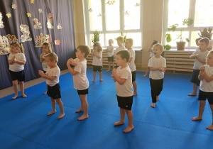 dzieci w strojach gimnastycznych ćwiczą na materacach