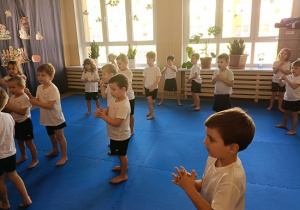 dzieci w strojach gimnastycznych ćwiczą na materacach