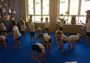 dzieci w strojach gimnastycznych ćwiczą na materacach