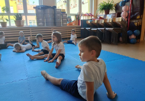 dzieci w strojach gimnastycznych ćwiczą na materacach