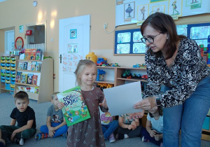 Pani Ewa wręcza dziewczynce książkę i dyplom