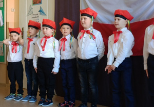 chłopcy w białych koszulach i czerwonych czapkach