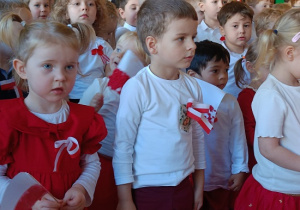 dzieci w białych bluzkach z kotylionami