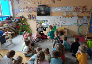 grupa dzieci słucha opowiadania czytanego przez nauczycielkę