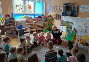 grupa dzieci słucha opowiadania czytanego przez nauczycielkę