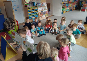grupa dzieci słucha opowiadania czytanego przez nauczycielkę