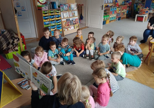 grupa dzieci słucha opowiadania czytanego przez nauczycielkę