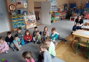 grupa dzieci słucha opowiadania czytanego przez nauczycielkę