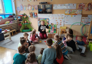 grupa dzieci słucha opowiadania czytanego przez nauczycielkę