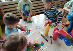 dzieci wykonują pracę plastyczną z wykorzystaniem farb