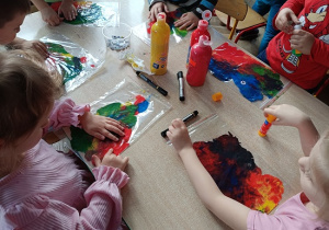 dzieci wykonują pracę plastyczną z wykorzystaniem farb