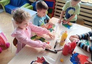 dzieci wykonują pracę plastyczną z wykorzystaniem farb