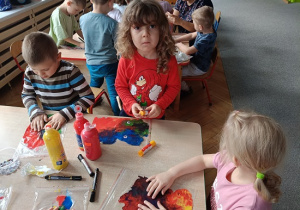 dzieci wykonują pracę plastyczną z wykorzystaniem farb