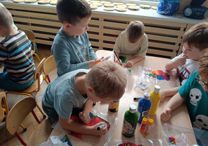 dzieci wykonują pracę plastyczną z wykorzystaniem farb