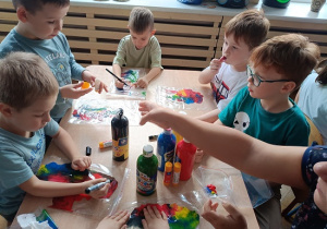 dzieci wykonują pracę plastyczną z wykorzystaniem farb