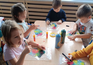 dzieci wykonują pracę plastyczną z wykorzystaniem farb