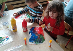 dzieci wykonują pracę plastyczną z wykorzystaniem farb