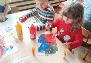 dzieci wykonują pracę plastyczną z wykorzystaniem farb