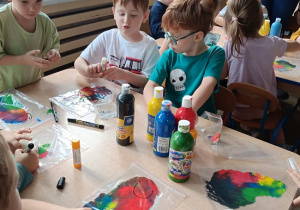 dzieci wykonują pracę plastyczną z wykorzystaniem farb