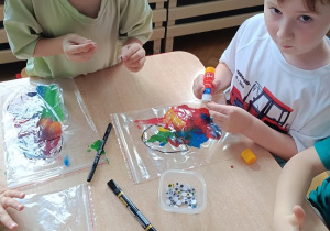 dzieci wykonują pracę plastyczną z wykorzystaniem farb