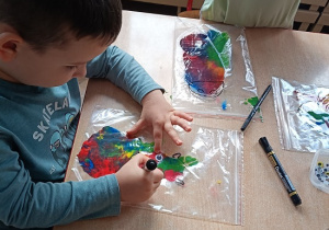 dzieci wykonują pracę plastyczną z wykorzystaniem farb