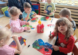 dzieci wykonują pracę plastyczną z wykorzystaniem farb