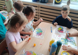 dzieci wykonują pracę plastyczną z wykorzystaniem farb