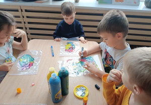 dzieci wykonują pracę plastyczną z wykorzystaniem farb
