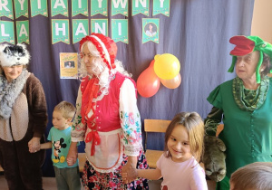 seniorzy w przebrania wspólnie z dziećmi tańczą w kole