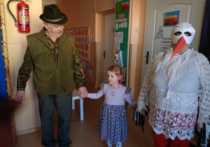 seniorzy w przebrania wspólnie z dziećmi tańczą w kole