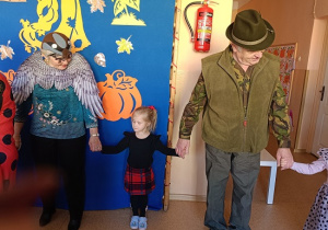 seniorzy w przebrania wspólnie z dziećmi tańczą w kole