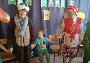 seniorzy w przebrania wspólnie z dziećmi tańczą w kole