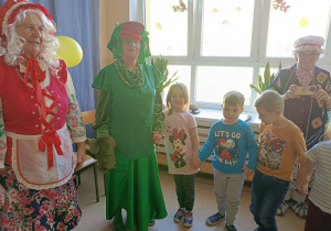 seniorzy w przebrania wspólnie z dziećmi tańczą w kole