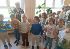 seniorzy w przebrania wspólnie z dziećmi tańczą w kole