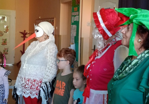 seniorzy w przebrania wspólnie z dziećmi tańczą w kole