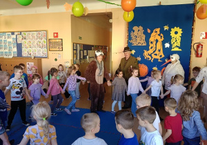 seniorzy w przebrania wspólnie z dziećmi tańczą w kole