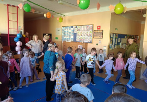 seniorzy w przebrania wspólnie z dziećmi tańczą w kole