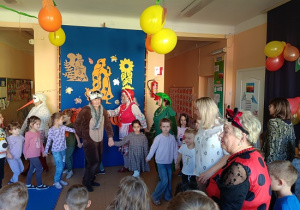 seniorzy w przebrania wspólnie z dziećmi tańczą w kole