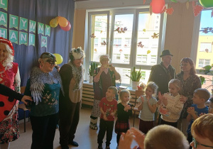 seniorzy w przebrania wspólnie z dziećmi tańczą w kole