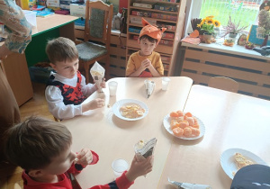 dzieci siedzą przy stolikach i jedzą popcorn